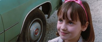 Movie still from “Matilda” (1996), directed by Danny DeVito – A young girl sitting in front of an old car; Close Up shot, High angle