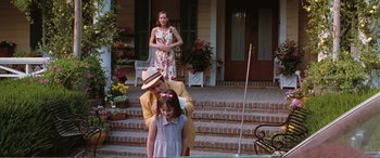 Movie still from “Matilda” (1996), directed by Danny DeVito – A man and a woman standing next to a little girl on a porch; Medium shot, Over the shoulder angle