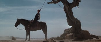 Movie still from “Maverick” (1994), directed by Richard Donner – A man on a horse holding a rope; Wide shot, Low angle