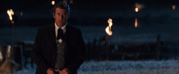 Movie still from “Maverick” (1994), directed by Richard Donner – A man in a suit and tie standing in front of a fire; Medium shot, Over the shoulder angle