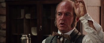 Movie still from “Maverick” (1994), directed by Richard Donner – An older man in a vest and bow tie; Close Up shot, Over the shoulder angle