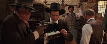 Movie still from “Maverick” (1994), directed by Richard Donner – A man wearing a hat and holding a gun looking at a box; Medium shot, Over the shoulder angle