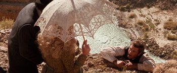 Movie still from “Maverick” (1994), directed by Richard Donner – A woman in a white dress holding an open umbrella; Wide shot, Overhead angle