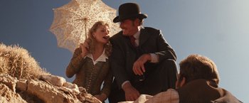 Movie still from “Maverick” (1994), directed by Richard Donner – A man and a woman sitting next to each other under an umbrella; Medium shot, Low angle