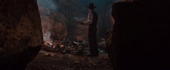 Movie still from “Maverick” (1994), directed by Richard Donner – A man in a cowboy hat is standing in front of an open fire; Wide shot, High angle