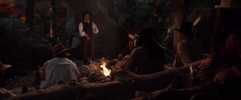 Movie still from “Maverick” (1994), directed by Richard Donner – A group of people sitting around a fire pit at night; Wide shot, High angle