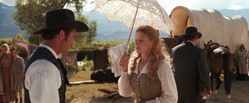 Movie still from “Maverick” (1994), directed by Richard Donner – A woman holding an umbrella while standing in a field; Medium shot, Over the shoulder angle