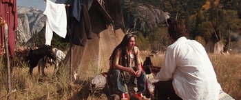 Movie still from “Maverick” (1994), directed by Richard Donner – A man sitting on the ground in front of a tent; Wide shot, Over the shoulder angle