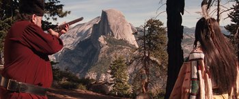 Movie still from “Maverick” (1994), directed by Richard Donner – A person walking on a trail in front of a large mountain; Extreme Wide shot, High angle