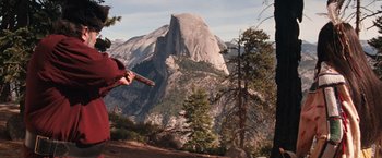 Movie still from “Maverick” (1994), directed by Richard Donner – A person is holding a gun in front of a mountain; Extreme Wide shot, High angle