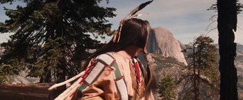 Movie still from “Maverick” (1994), directed by Richard Donner – A person in a native american outfit walking in front of a mountain; Wide shot, Low angle