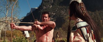 Movie still from “Maverick” (1994), directed by Richard Donner – A man is holding a bow and arrow in the woods; Medium shot, Over the shoulder angle