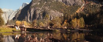 Movie still from “Maverick” (1994), directed by Richard Donner – A group of people riding horses near a body of water; Extreme Wide shot, High angle
