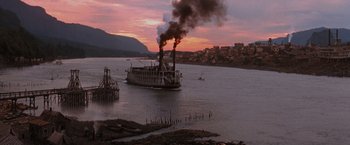 Movie still from “Maverick” (1994), directed by Richard Donner – A boat traveling down a river at sunset with smoke billowing out of it; Extreme Wide shot, High angle