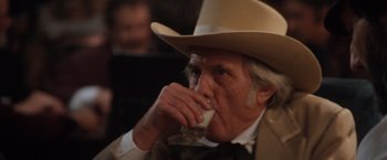 Movie still from “Maverick” (1994), directed by Richard Donner – An older man in a cowboy hat drinking a glass of milk; Close Up shot, Over the shoulder angle