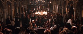 Movie still from “Maverick” (1994), directed by Richard Donner – A group of people sitting around a table in front of a fireplace; Wide shot, High angle