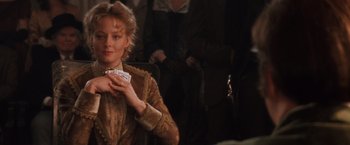 Movie still from “Maverick” (1994), directed by Richard Donner – A woman in a brown dress holding a piece of paper in her hand; Medium shot, Over the shoulder angle