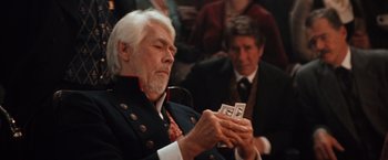 Movie still from “Maverick” (1994), directed by Richard Donner – An older man holding a stack of money; Close Up shot, Over the shoulder angle