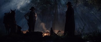 Movie still from “Maverick” (1994), directed by Richard Donner – Two people standing in front of a fire in the woods; Wide shot, Low angle