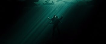 Movie still from “Max Payne” (2008), directed by John Moore – A man in a jacket is swimming underwater; Wide shot, Overhead angle