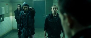 Movie still from “Max Payne” (2008), directed by John Moore – Two men in black jackets in a dark room; Medium shot, Over the shoulder angle