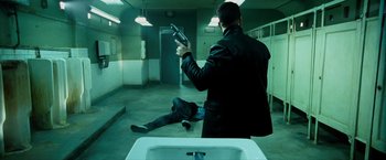 Movie still from “Max Payne” (2008), directed by John Moore – A man holding a gun while standing next to a man laying on the ground; Wide shot, High angle