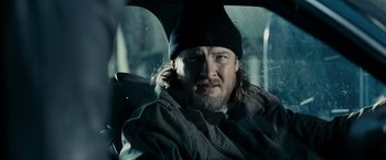 Movie still from “Max Payne” (2008), directed by John Moore – A man with long hair and beard sitting in the back of a car; Close Up shot, Over the shoulder angle