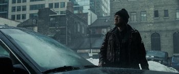 Movie still from “Max Payne” (2008), directed by John Moore – A man standing next to a car in the rain; Medium shot, Low angle