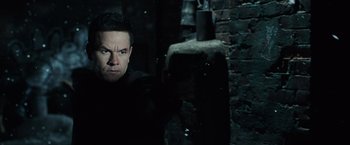 Movie still from “Max Payne” (2008), directed by John Moore – A man standing in the dark in front of a brick wall; Close Up shot, Over the shoulder angle