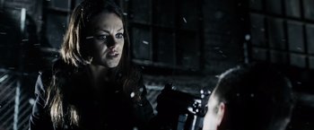 Movie still from “Max Payne” (2008), directed by John Moore – A woman in a black leather jacket is holding a gun and looking at the camera; Close Up shot, Over the shoulder angle