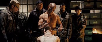 Movie still from “Max Payne” (2008), directed by John Moore – A group of men standing next to each other in a room; Medium shot, Over the shoulder angle
