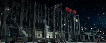 Movie still from “Max Payne” (2008), directed by John Moore – A building that has a lot of smoke coming out of it; Extreme Wide shot, Low angle