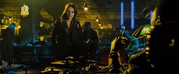 Movie still from “Max Payne” (2008), directed by John Moore – A woman standing next to a man holding a gun; Medium shot, Over the shoulder angle