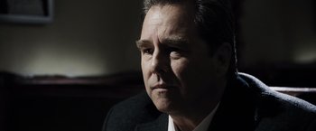 Movie still from “Max Payne” (2008), directed by John Moore – A person wearing a suit and tie; Close Up shot, Over the shoulder angle