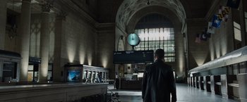 Movie still from “Max Payne” (2008), directed by John Moore – A man standing in front of a clock in a train station; Wide shot, Low angle