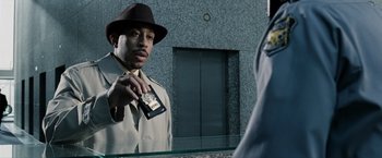 Movie still from “Max Payne” (2008), directed by John Moore – A man in a hat holding a cell phone in front of a mirror; Close Up shot, Over the shoulder angle