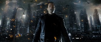 Movie still from “Max Payne” (2008), directed by John Moore – A man in a black jacket standing in front of a city; Medium shot, Low angle