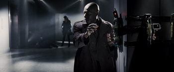 Movie still from “Max Payne” (2008), directed by John Moore – A man in a trench coat holding a cell phone in his hand; Medium shot, High angle