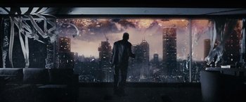 Movie still from “Max Payne” (2008), directed by John Moore – A man standing in front of a large picture of a city; Wide shot, Low angle