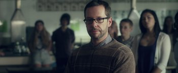 Movie still from “Max Steel” (2016), directed by Stewart Hendler – A man in a brown sweater and glasses looks at the camera; Close Up shot, Over the shoulder angle