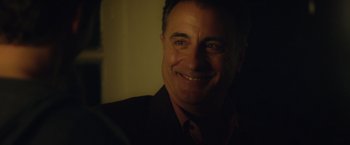 Movie still from “Max Steel” (2016), directed by Stewart Hendler – A person wearing a suit and smiling; Close Up shot, Over the shoulder angle