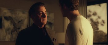 Movie still from “Max Steel” (2016), directed by Stewart Hendler – A man in a suit talking to another man in a room; Close Up shot, Over the shoulder angle
