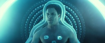 Movie still from “Max Steel” (2016), directed by Stewart Hendler – A man in a body suit is sitting in a chair; Medium shot, Overhead angle