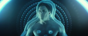 Movie still from “Max Steel” (2016), directed by Stewart Hendler – A man in a body suit is sitting in a chair; Close Up shot, High angle