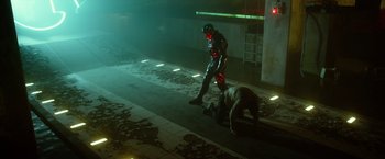 Movie still from “Max Steel” (2016), directed by Stewart Hendler – A man in a black suit is standing next to another man in a black suit; Wide shot, High angle