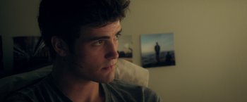 Movie still from “Max Steel” (2016), directed by Stewart Hendler – A man sitting in front of a picture of a person; Close Up shot, Over the shoulder angle