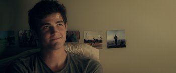 Movie still from “Max Steel” (2016), directed by Stewart Hendler – A young man sitting on a bed in front of some pictures; Close Up shot, Over the shoulder angle
