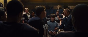 Movie still from “McFarland, USA” (2015), directed by Niki Caro – A group of young men standing around each other in a room; Medium shot, Over the shoulder angle