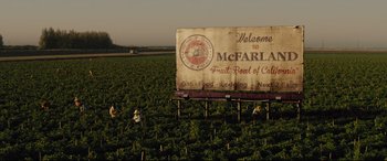 Movie still from “McFarland, USA” (2015), directed by Niki Caro – A sign that says welcome to mcfarland fruit bowl of calfornia; Extreme Wide shot, High angle
