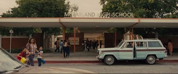 Movie still from “McFarland, USA” (2015), directed by Niki Caro – A group of people standing in front of a building; Extreme Wide shot, High angle